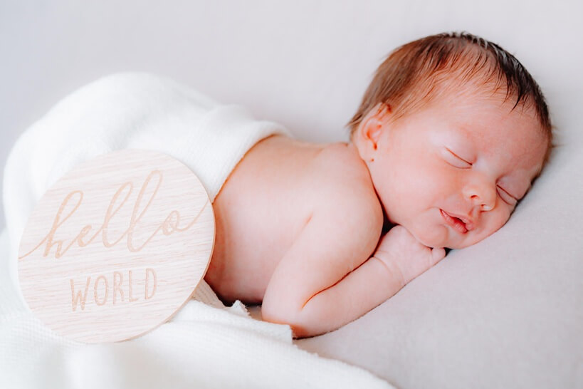 Neugeborenenfoto – schlafendes Baby mit „Hello World“-Schild im Fricktal