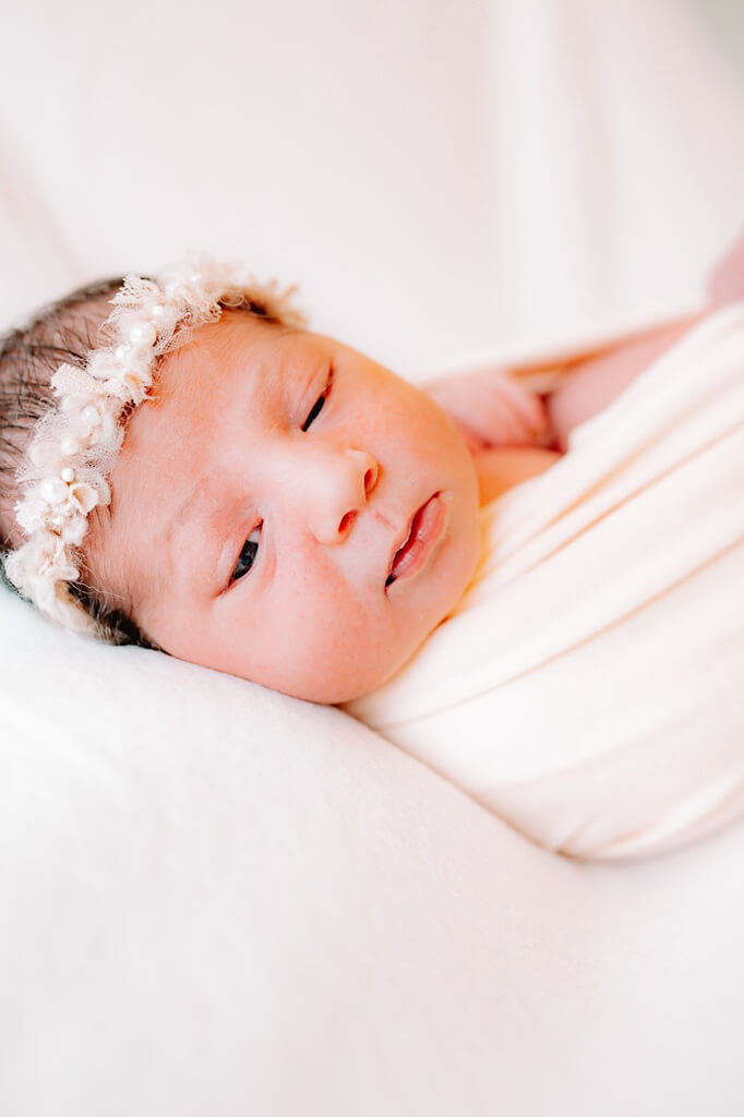 Neugeborenenfoto zarte Nahaufnahme Baby mit Blumenstirnband