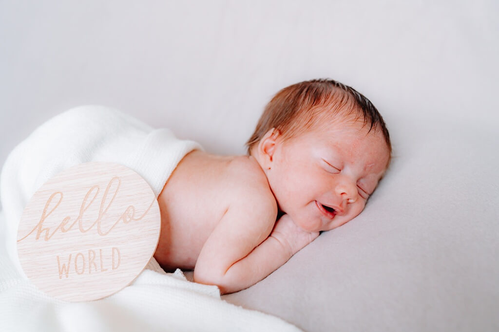 Newborn Shooting Baby schläft mit Hello World Schild