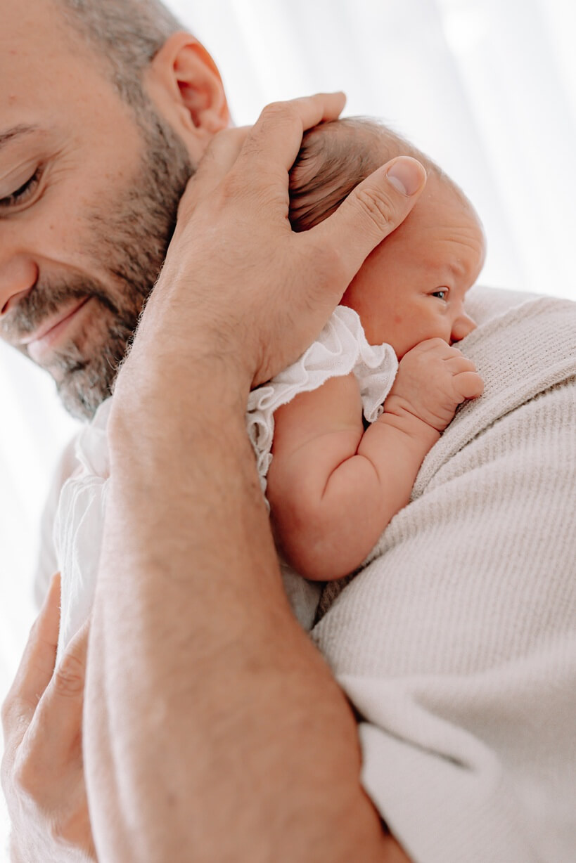 Newborn Shooting Rheinfelden – Papa hält sein Neugeborenes liebevoll im Arm